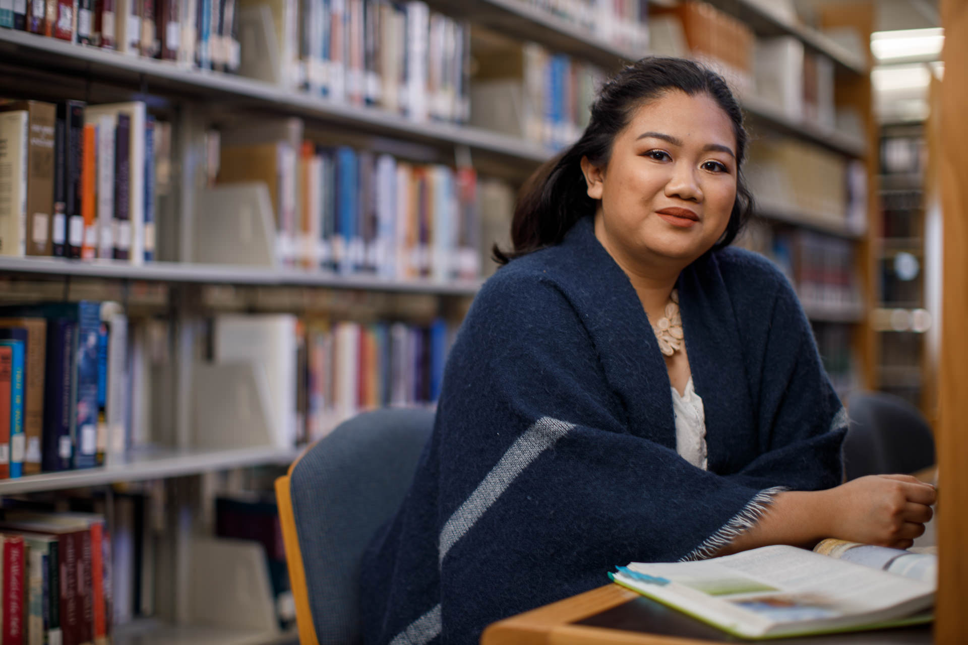 Girl at table in library with open text book