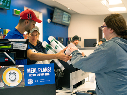 A barista handing a cup to a customer