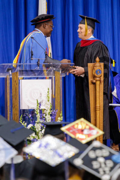 Dr. Abson Joseph presents the 2026 Professor of the Year award to Dr. Keith Koteskey at Bethel University commencement.