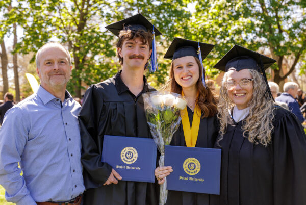 Wesley Oke '26 with fiance and parents holding up diplomas at Bethel graduation