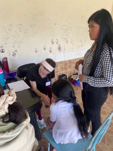 Bethel nursing student Peyton Dickinson assists a patient during a medical clinic in Ecuador while working alongside a translator.