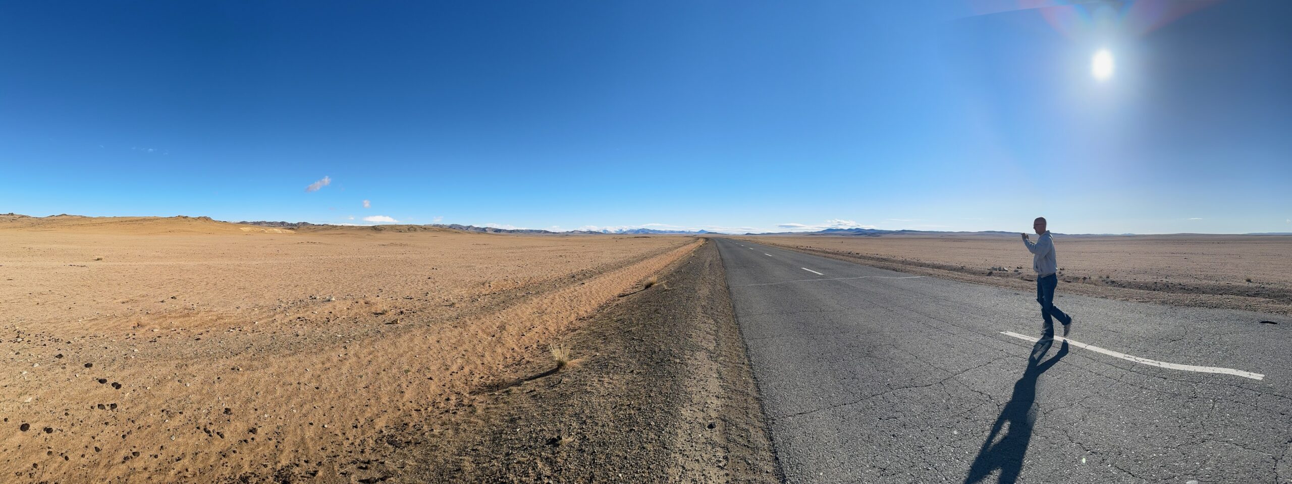 A long highway stretches through Mongolia's open desert landscape while a Task Force member photographs the scenery.
