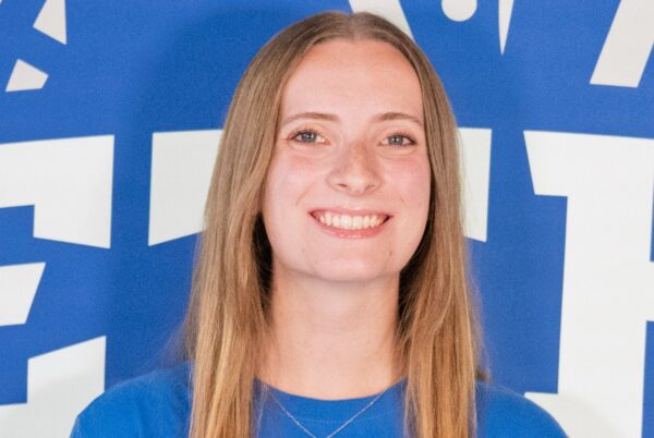 Isabela Nuet, head coach of the Bethel University men’s and women’s swim and dive programs, smiles for a portrait in front of a Bethel backdrop.