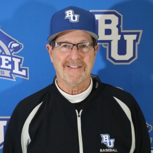 Rob Bjorkland ’79, recipient of Bethel University’s 2026 Timothy Award for Outstanding Service, wearing a Bethel baseball cap and jacket in front of a blue BU Athletics backdrop.
