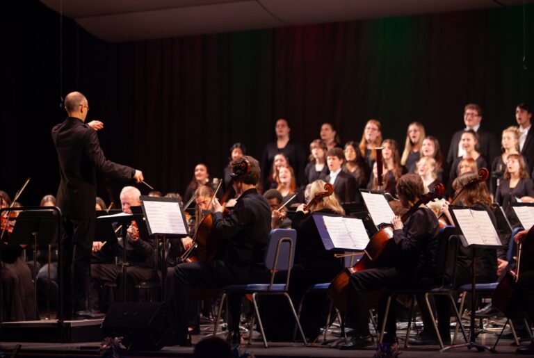 Bethel University choir and orchestra perform together on stage during a 2025-26 music concert in Everest-Rohrer Auditorium.
